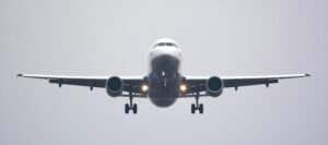 A commercial airliner captured head-on, preparing to land against a cloudy sky.