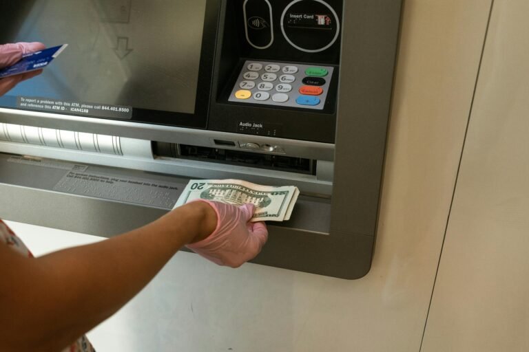 A person wearing gloves withdrawing cash from an ATM machine showcasing money handling and hygiene.